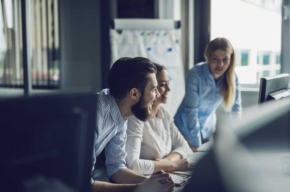 Tre personer sidder og arbejder ved en computer