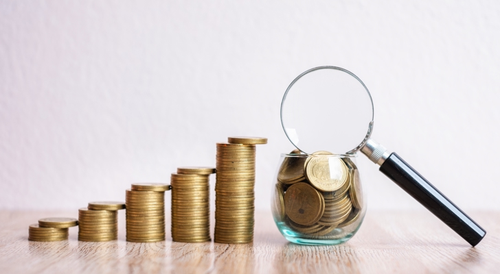 Mønter i stakke og i glas med en lup ovenpå