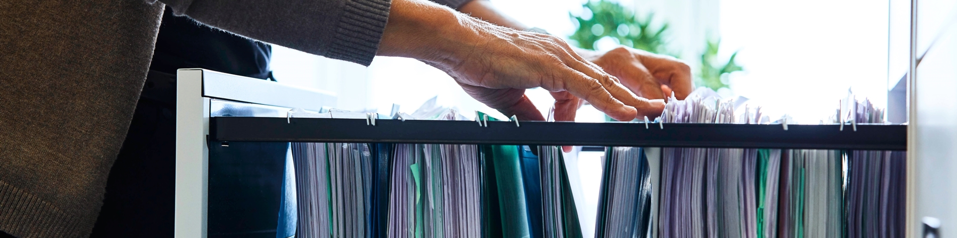 Kvinde kigger efter sag i sagsarkivskuffe