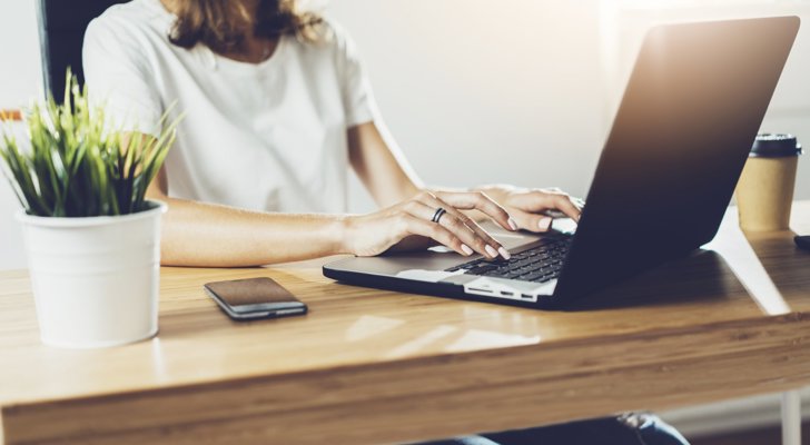 Kvinde sidder ved sin bærbar på sin hjemmearbejdsplads